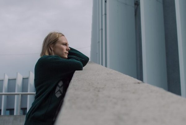 woman in black jacket standing near white concrete building during daytime