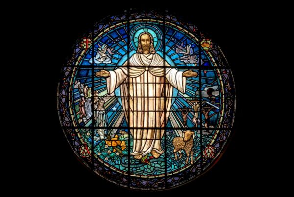 A circular stained glass window depicting a central figure with arms outstretched